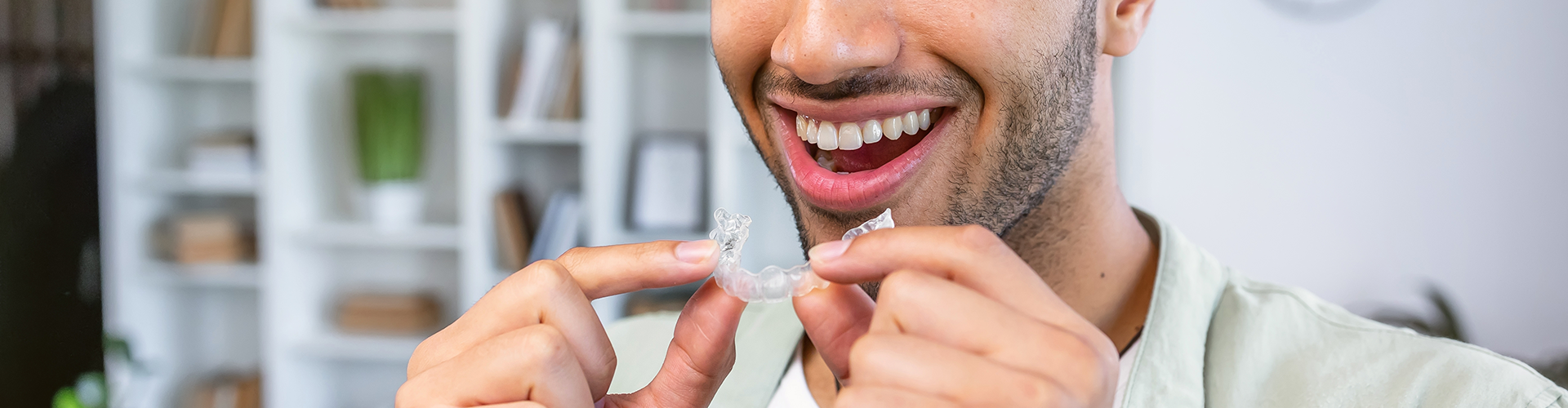 smiling man holding clear aligner